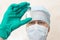 Man in doctor`s cap and mask holds in sterile glove a vial with a white powder