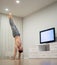 A man does handstand, keeps balance watching TV. Concept of individuality, creativity and self-confidence