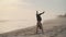 Man does headstand during training at beach, standing on arms, then sits on twine