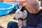 Man with dog. English Bull Terrier white dog in company with his owner sitting and enjoying in the garden outdoor and petting dog.