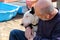 Man with dog. English Bull Terrier white dog in company with his owner sitting and enjoying in the garden outdoor and petting dog.