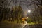 Man with dog in front of a building in a Spooky park at a rainy night