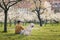 Man with dog sitting in blooming city park during spring day