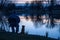 man with dog sitting on chair, reflective lake at dusk