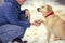 The man with the dog sitting in a snowy field