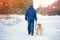 A man with the dog walking along a snow-covered road