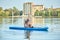 Man doing exercise difficult yoga pose on paddle board at daytime on lake.