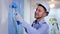 man doing finishing work in construction helmet using roller to paint walls during painting repairs