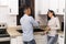 man doing housework in the kitchen while talking with his wife.