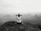 Man is doing Yoga pose on the rocks peak within misty morning