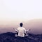 Man is doing Yoga pose on the rocks peak within misty morning