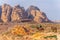 A man on a donkey is looking at Al Habis mountain behind Qasr al Bint in Petra, Jordan