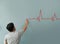 Man drawing heartbeat with red chalk on wall.