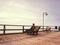 Man dreaming sitting on a wooden pier near the water