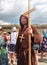 Man dressed as a medieval priest, a monk with a wooden cross with a staff in his hand and with a wooden cross on his neck among