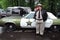 A man dressed as sheriff stands by an old car