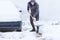 Man dressed in jacket cleaning snow around his car.