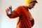 Man dressed in orange and wearing a yellow cap using a blue asthma inhaler to prevent an asthma attack