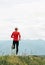 Man dressed in red long sleeve shirt runs by the road with mountain background vertical shoot