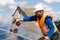 Man with drill screwdriver installs panels at a solar power plant.