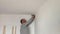A man drills white wall, drill, concrete, electric drill, Close up hands hold electric drill in white room.