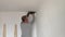 A man drills white wall, drill, concrete, electric drill, Close up hands hold electric drill in white room.