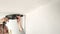 A man drills white wall, drill, concrete, electric drill, Close up hands hold electric drill in white room.