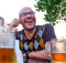 The man drinking cider jokes, smiles. A young man drinks cider in an open cafe and looks into the distance. Entertainment concept