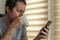 Man drinking coffee and using mobile phone at home