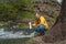 Man drinking coffee from white thermos near mountain river