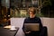 Man drinking cup of coffee in a restaurant on the terrace. Freelancer outdoor with a laptop, has breakfast with croissants.