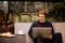 Man drinking cup of coffee in a restaurant on the terrace. Freelancer outdoor with a laptop, has breakfast with croissants.