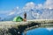 Man drinking tea near tent in mountains.