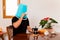 Man drinks coffee with a blue bucket on his head, flowers in the background