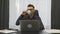 Man drinks coffee espresso in modern office sitting at workplace. Young businessman in suit and glasses drinking coffee at office