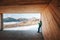 Man drinks a hot drink in wooden hangar with mountains panorama