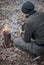 A man drinks tea from an iron mug and looks at the fire