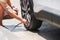 Man driver hand inflating tires of vehicle, removing tire valve nitrogen cap for checking air pressure and filling air on car