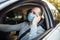 A man drives a car and adjusts medical mask during coronavirus outbreak. Taxi driver delivers his passanger to the destination.