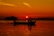 Man driving a boat with the setting sun in the background