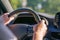 A man driving a car firmly holds on to the steering wheel with his hands. Driving a car on a weekend trip