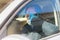 A man driving in a car with a protective mask and gloves is talking on the phone, epidemia of coronavirus. Work during quarantine