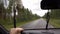 Man driving a car on public road during heavy rainfall with water droplets on windshield and rubber wipers