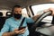Man Driving Car Using Smartphone Wearing Face Mask In Automobile