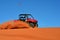 Man Driving a Four Wheeler on Sand with Blue Sky