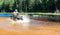 Man driving motocross ATV quad through splashing river lake water with high speed. Foy, Foyross Lake, Sudbury, Canada.