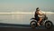 Man is driving motorcycle over sandy beach of ocean