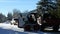 A man is driving a small front loader machine and unloading tree branches into a trailer as part of a tree trimming job