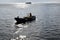 Man driving small tugboat toward the sea shore