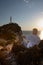 man with drone at the cliff near sea sunset above the lighthouse